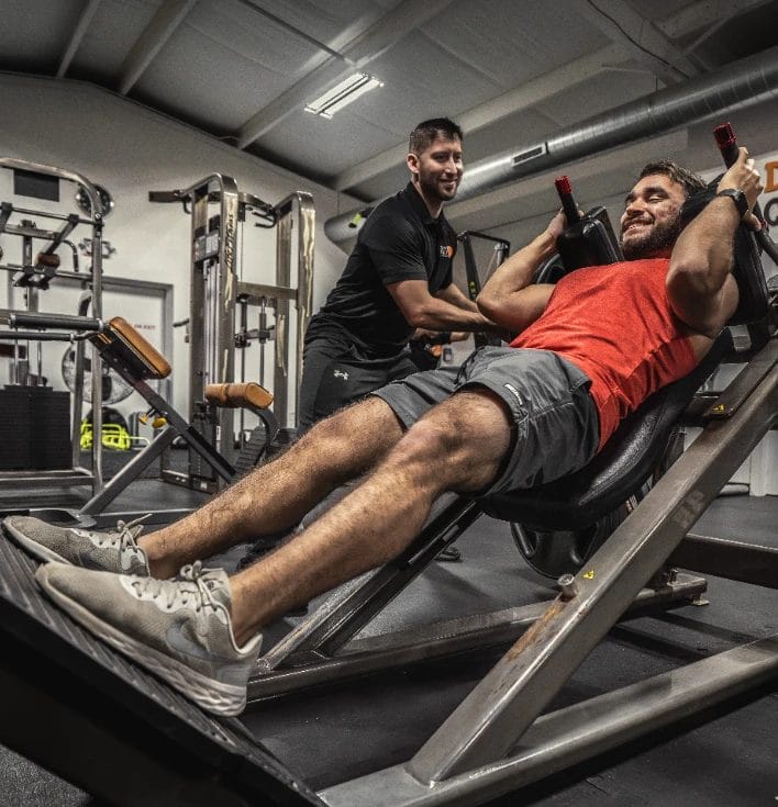Member performing a leg press with trainer support at Repz Fitness