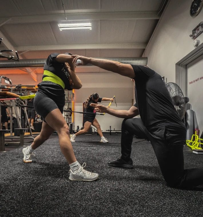 Trainer assisting a member with a mobility and stretching exercise at Repz Fitness